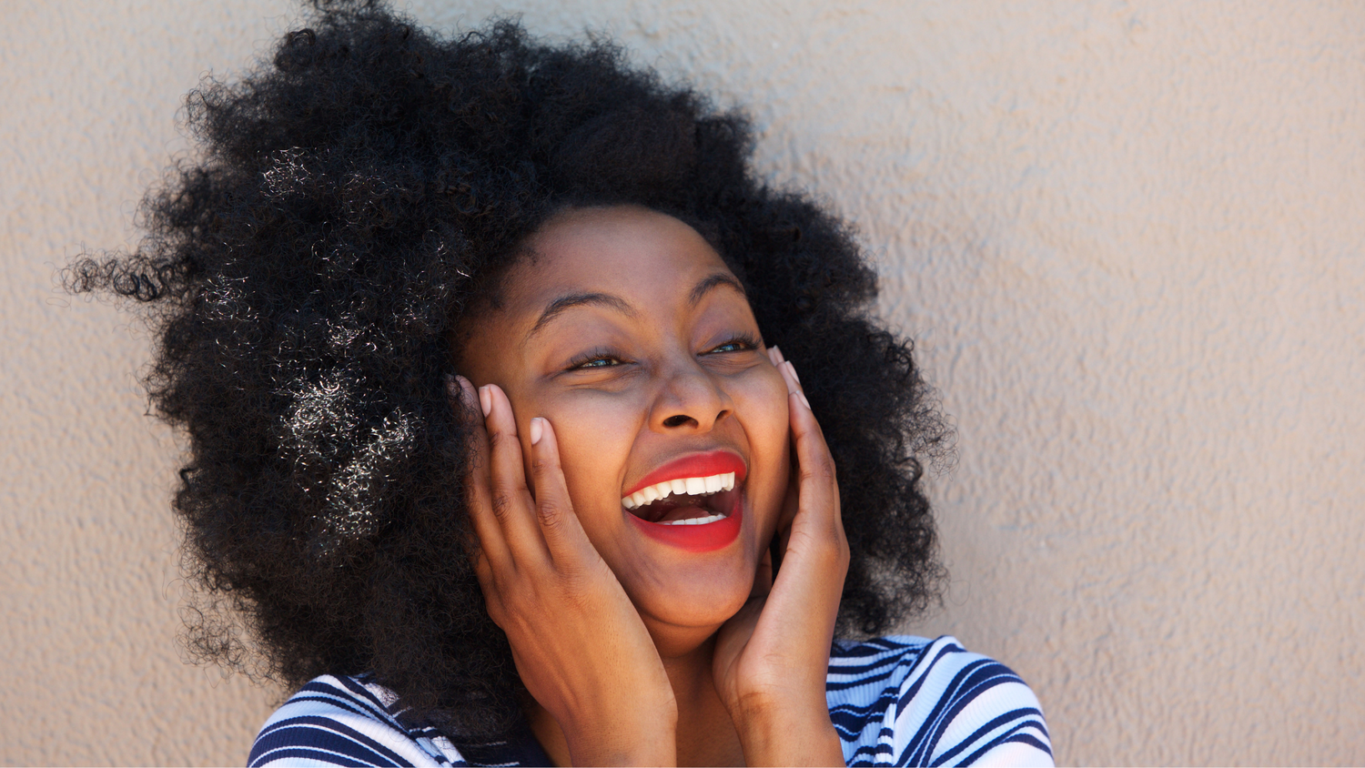 Black woman smiling with hands on cheeks